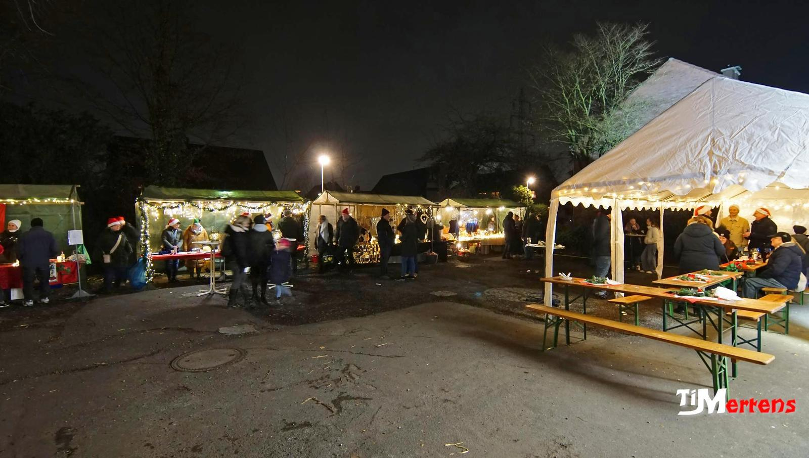 Ansicht des Adventmarkt auf dem Schulhof mit Ständen, Menschen und weihnachtlicher Beleuchtung